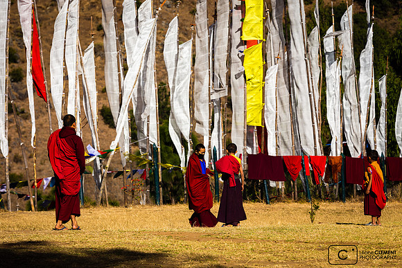 Moines du temple Drukpa Kuenley (Fou Divin) devant drapeaux à prières